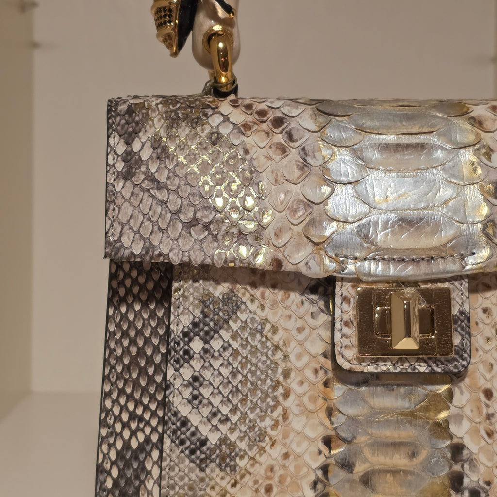 Biagini Art Bag –

Handcrafted in Bologna, Italy since 1968, the Biagini Art Bag is a masterclass in exquisite Italian artistry and uncompromising luxury. Designed to make a statement, this piece showcases genuine python finishes paired with rich, sumptuous suede interior lining. Every detail is meticulously finished, featuring a distinctive hand-painted enameled brass handle and gleaming gold-tone hardware.

Craftsmanship: Made in Italy
Brought to you by Rise And Shine Haven - BellaBarra.store
