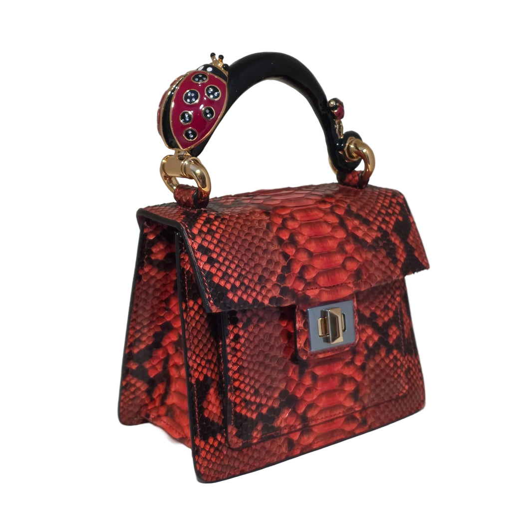 Biagini Art Bag –

Handcrafted in Bologna, Italy since 1968, the Biagini Art Bag is a masterclass in exquisite Italian artistry and uncompromising luxury. Designed to make a statement, this piece showcases genuine python finishes paired with rich, sumptuous suede interior lining. Every detail is meticulously finished, featuring a distinctive hand-painted enameled brass handle and gleaming gold-tone hardware.

Craftsmanship: Made in Italy
Brought to you by Rise And Shine Haven - BellaBarra.store
